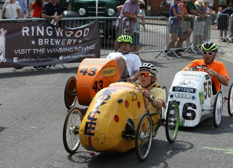 Three pedal cars each with drivers, racing head to head