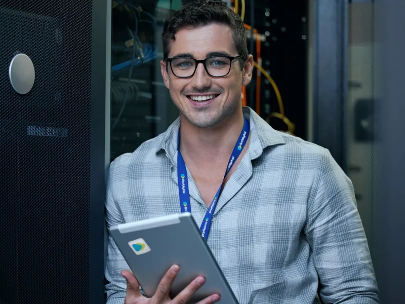 A man in a datacentre, smiling towards the camera and wearing a Find Digital lanyard